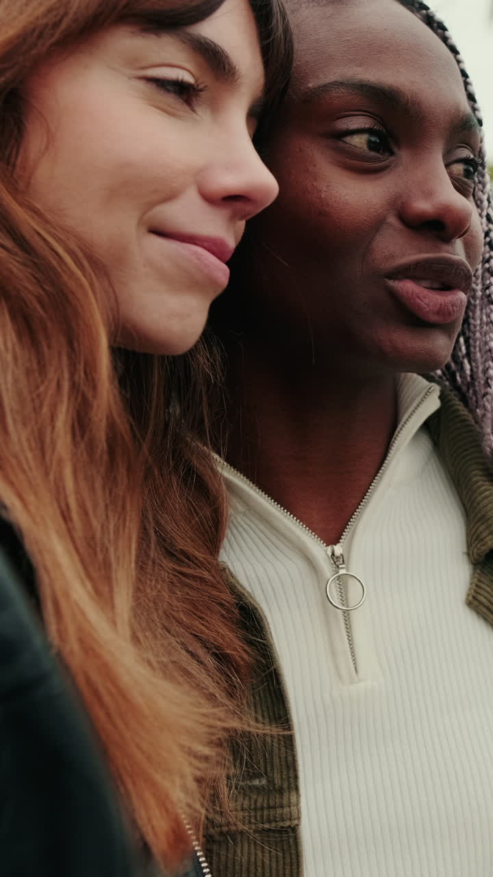 Primo piano di due donne felici e diverse che sorridono all'aperto.