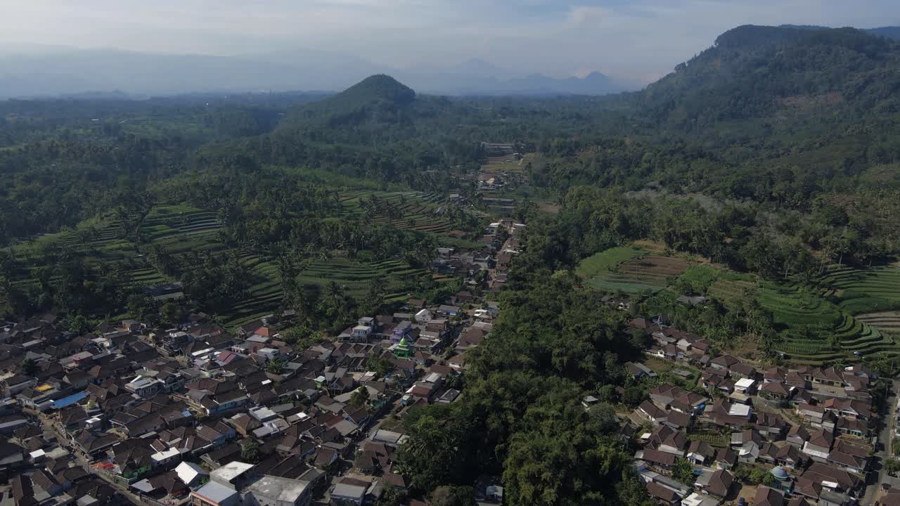 Bidikan udara desa pedesaan Indonesia dengan sawah bertingkat dan tanaman hijau tropis
