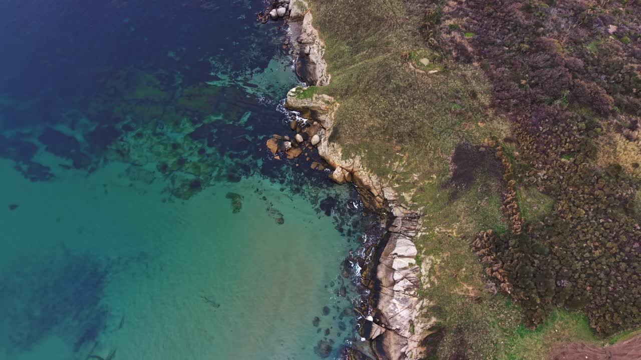 Coastal cliffs meet the turquoise waters along a serene shoreline
