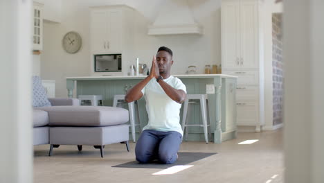 focused african american man practising yoga meditation in sunny living room, slow motion