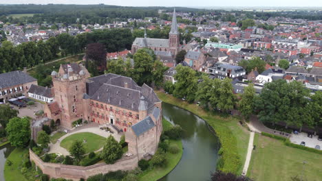 kasteel-huis-bergh,-the-netherlands:-aerial-view-in-orbit-and-near-the-beautiful-castle-and-appreciating-the-moat-and-the-nearby-church