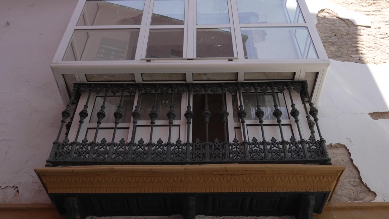 Balcone tradizionale in ferro battuto su facciata storica di Siviglia.