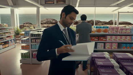 man in a suit writing in a grocery store overlooking the ocean