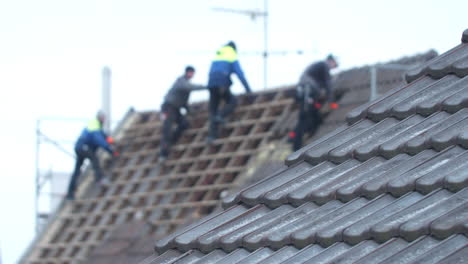 Statische-Aufnahme-Von-Vier-Männern,-Die-An-Einem-Alten-Dach-Arbeiten