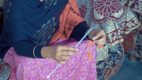 traditional indian woman watching her knitting and start to knit new row with black wool