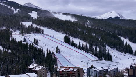 snow making half pipe big air jump ski snowboard gondola ski lift aerial drone cinematic copper mountain colorado winter december christmas ski runs trails landscape cloudy rocky mountains backwards