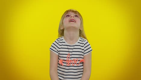 a young girl with blonde hair smiles while covering her eyes with her hands