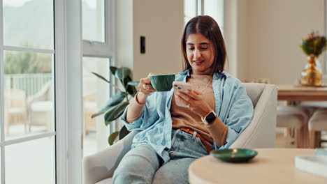 Woman drinking coffee and using phone indoors
