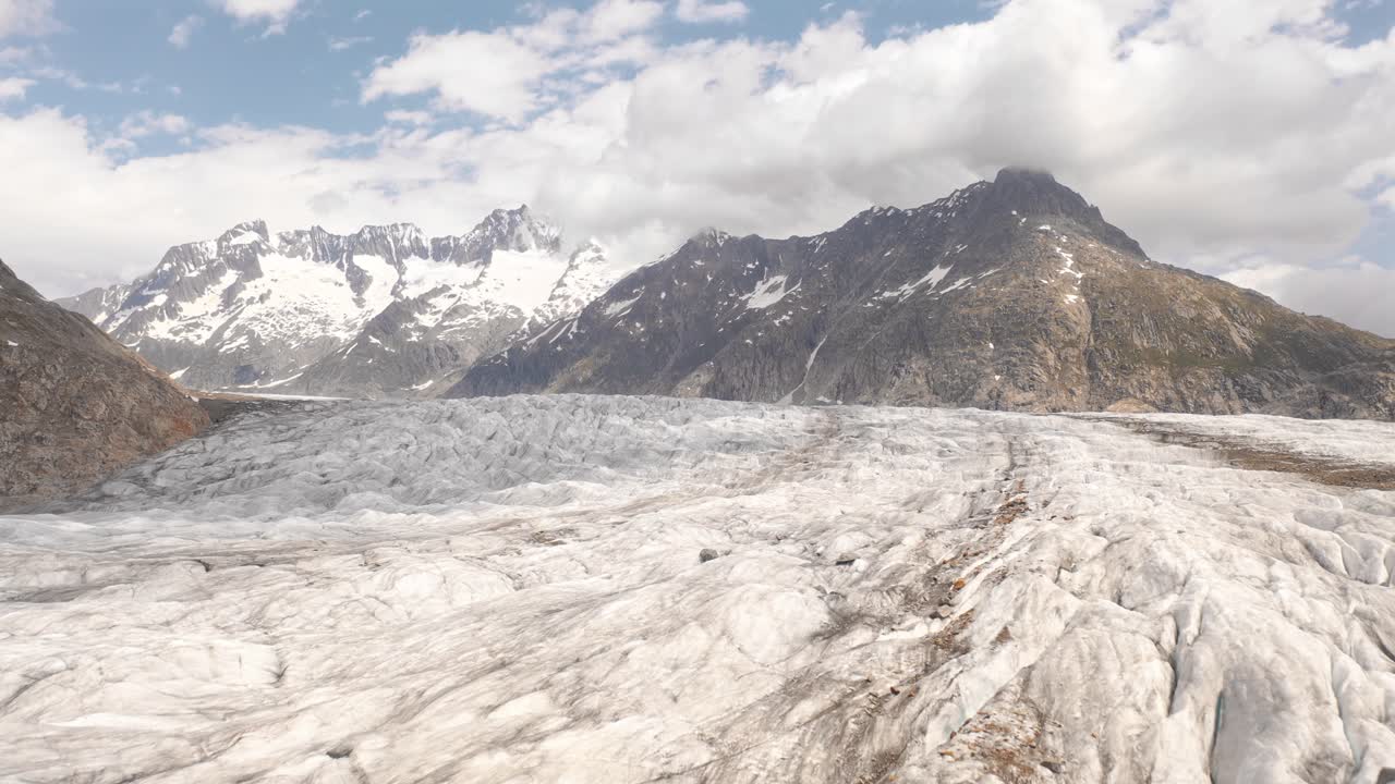 Snow-covered glacier with dramatic mountains and clouds in Norway's landscape