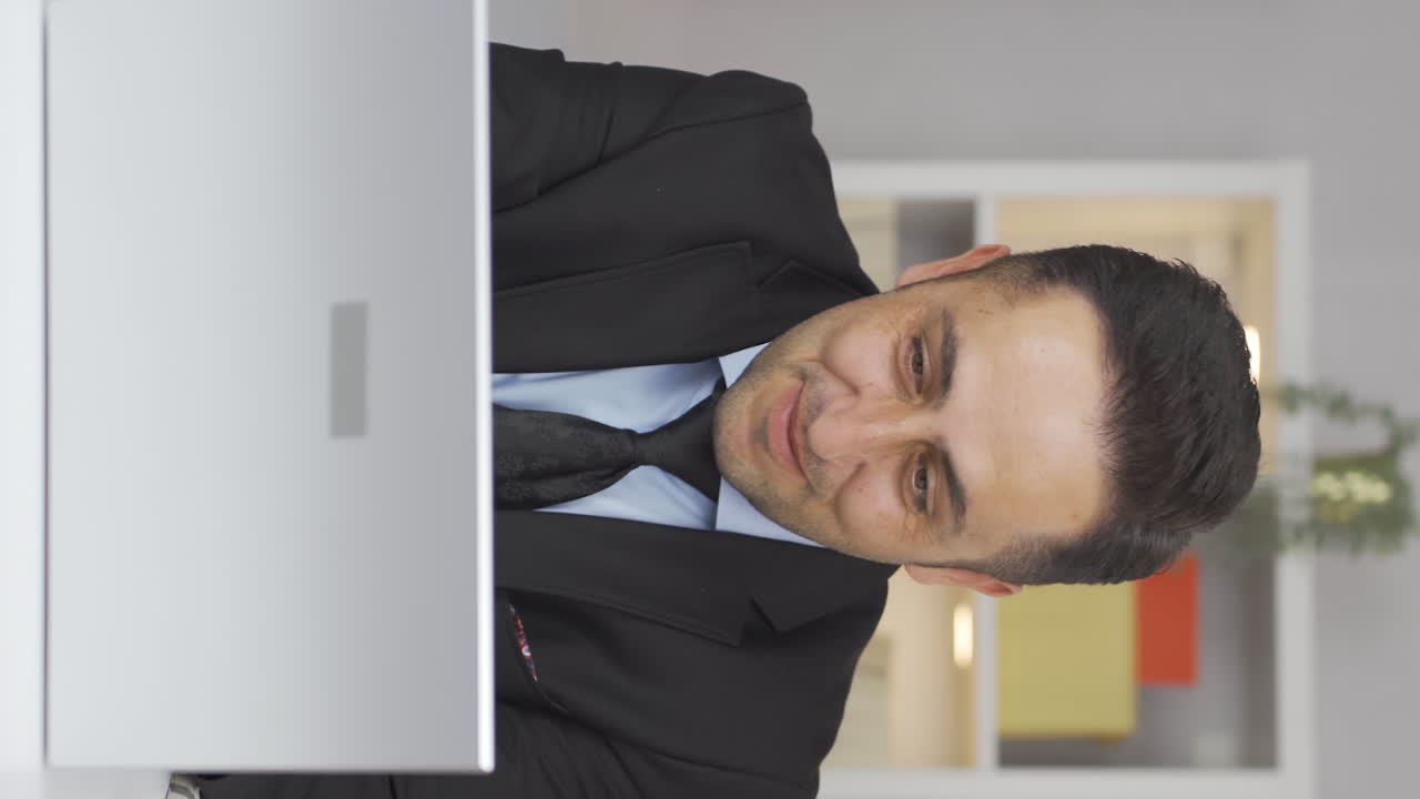 video vertical de un trabajador de oficina en casa que se alegra de lo que ve en la computadora portátil.