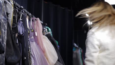 A Beautiful Positive Woman Chooses a Black Evening Dress in a Shopping Mall. A beautiful positive woman chooses a black evening dress in a shopping mall, in an elegant clothing boutique. Selection of evening clothes for the celebration