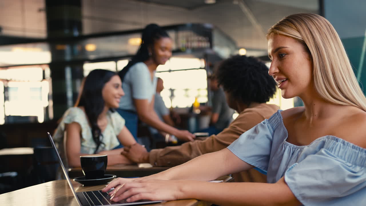 Woman Using Laptop Remote Working In Busy Coffee Shop