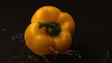 Yellow-pepper-falling-on-wet-black-surface