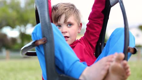 Junge-Entspannt-Sich-An-Einem-Sonnigen-Tag-Auf-Den-Schaukeln-Auf-Dem-Spielplatz