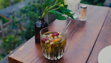 herbal tea glass cup on wooden table with jar of flowers