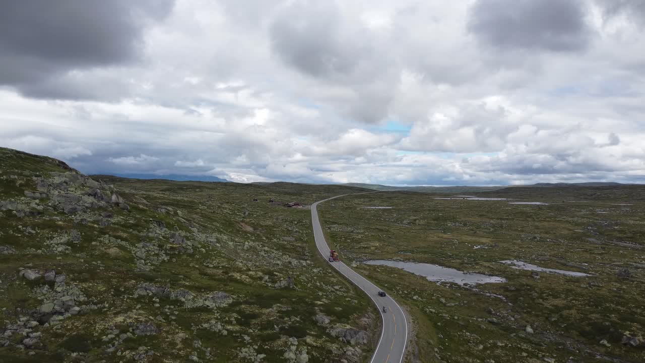 Traffic on Norways mountain crossing road rv7 between east and west - Hardangervidda national park upward moving aerial at overcast summer day