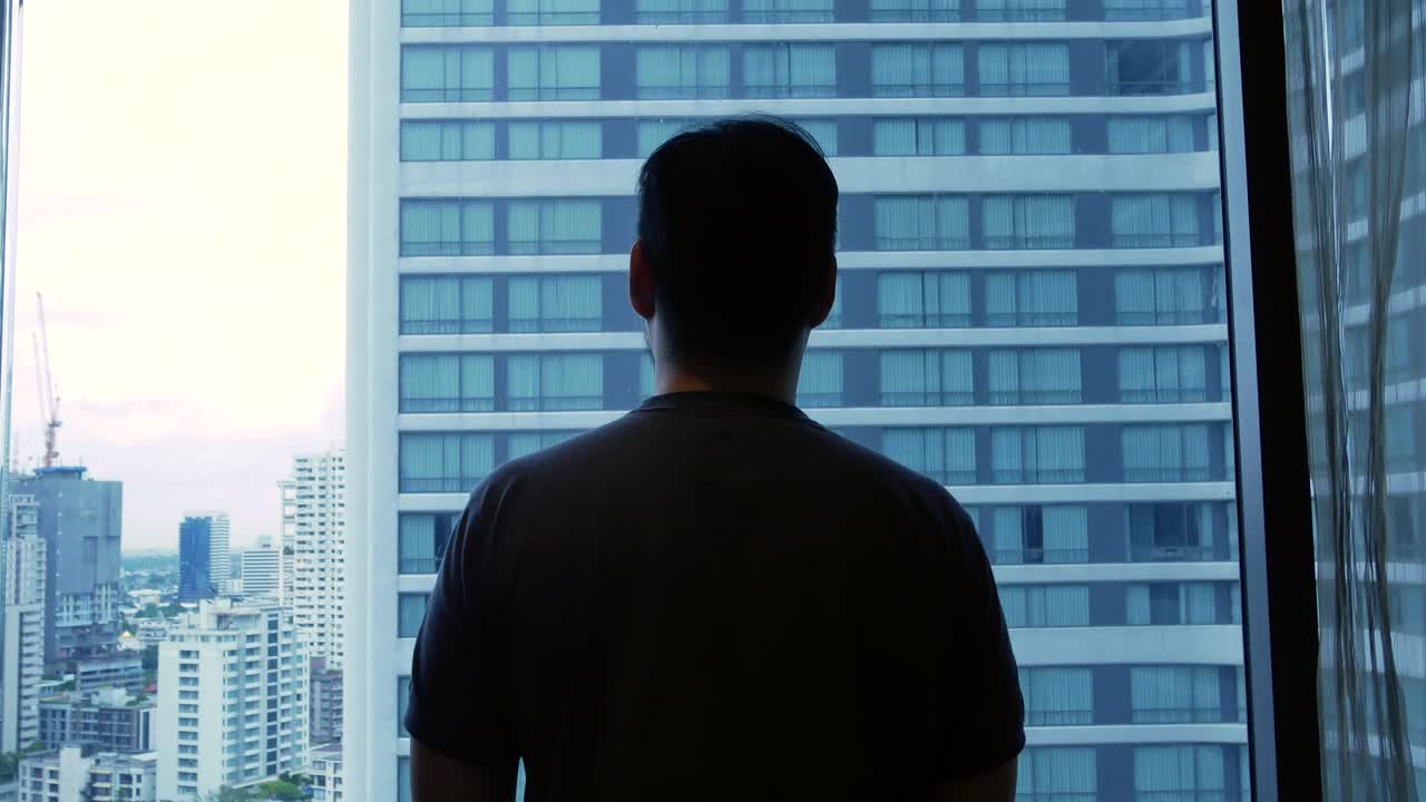 un hombre tiene una cortina abierta con vistas a la ciudad de rascacielos para respirar aire fresco