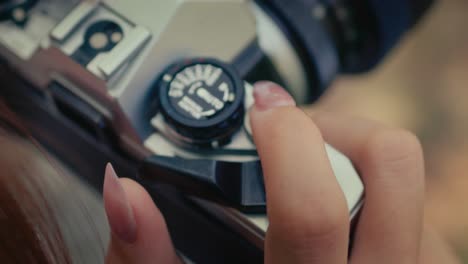 close up on female hands with long nails turning the film advance lever on old vintage retro film camera