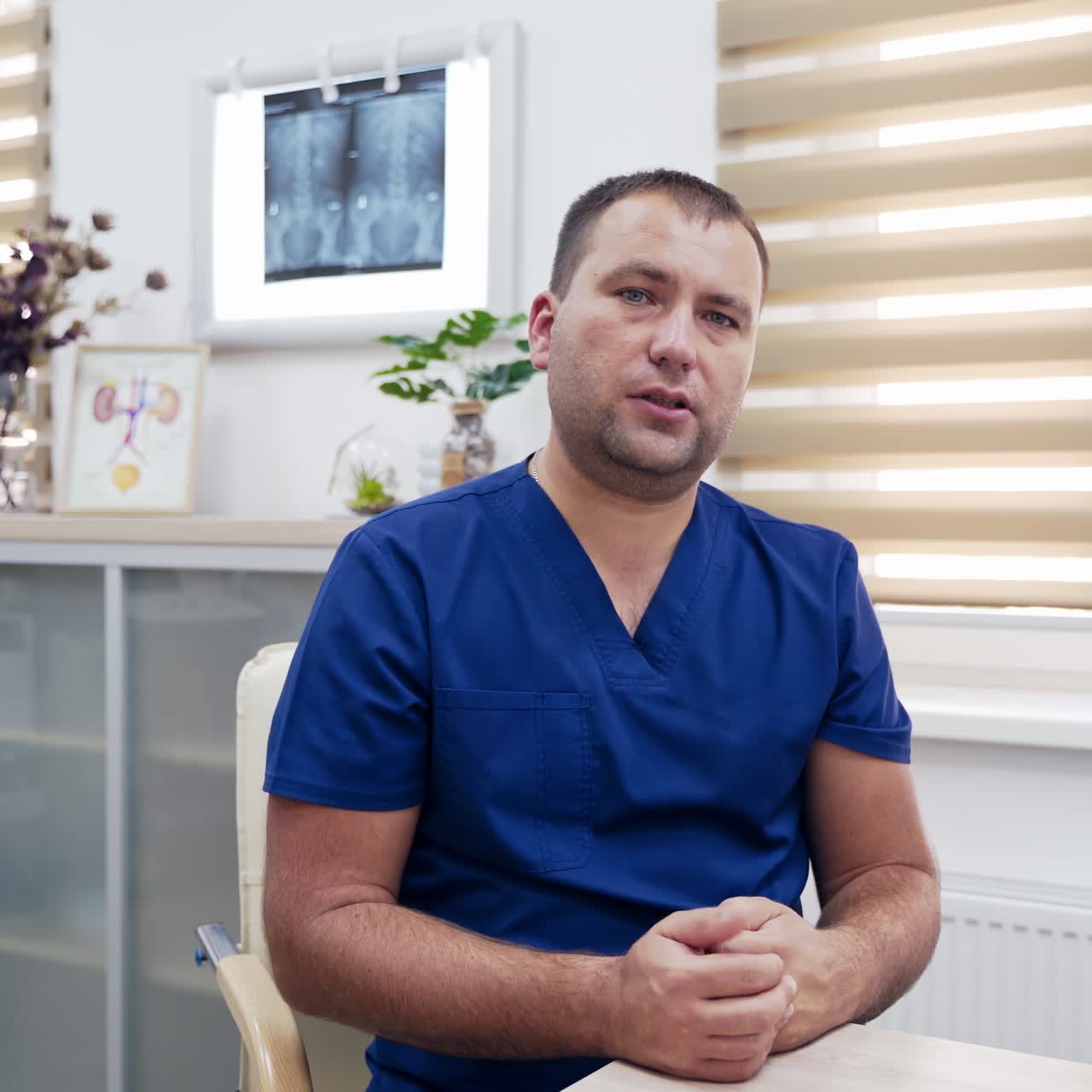 Doctor consults patients through the camera. Professional male therapist talking about possible ways of health treatment while sitting in clinic. Telemedicine concept.