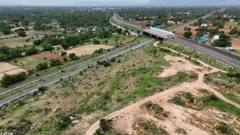 Aerial-view-of-a-serene-sunrise-over-the-highway-with-light-traffic-train-tracks-passing-through-the-bridge