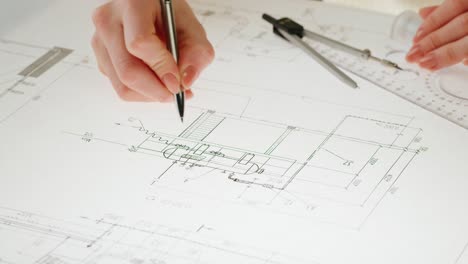 hands working on architectural blueprints with drafting tools