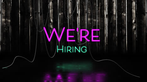 animation of we're hiring text in pink and blue neon, with hanging cables on black background