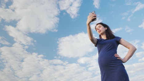 mujer embarazada tomando una foto contra el cielo azul