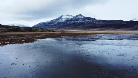 Snowy-rocky-mountains-at-lakeside-on-winter-day