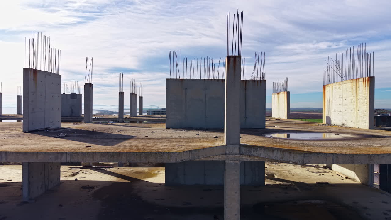 Abandoned construction site stands as a testament to halted dreams under a vast sky filled with soft clouds