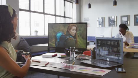 Biracial-Geschäftsfrau-Arbeitet-Mit-Laptop-Und-Hält-Kamera-Im-Büro