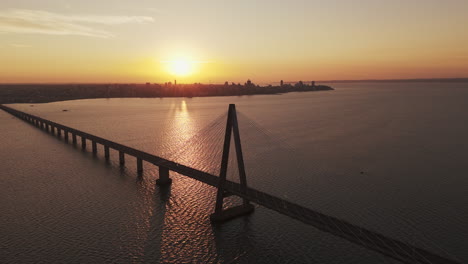 Drone-shot-back-of-the-San-Roque-González-de-Santa-Cruz-International-Bridge-at-sunset-and-panoramic-horizon,-Argentina