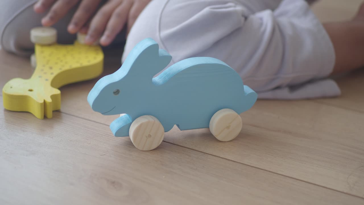 Baby playing with wooden animal toys on a wooden floor