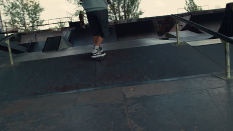 extreme boy jumping with scooter on ramp at city skate park.