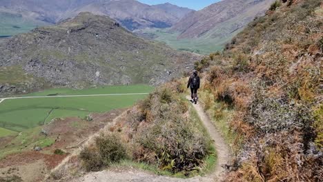 middle aged latina woman hiking down a mountain on a beautiful clear day in wanaka new zealand