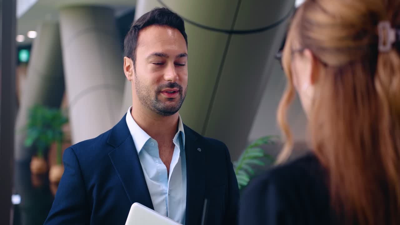 European Businessman In A Dark Suit Speaking To His Female Colleague In A Modern Office. - closeup shot