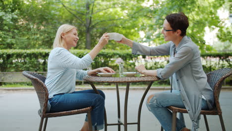 two women enjoying coffee in a park cafe