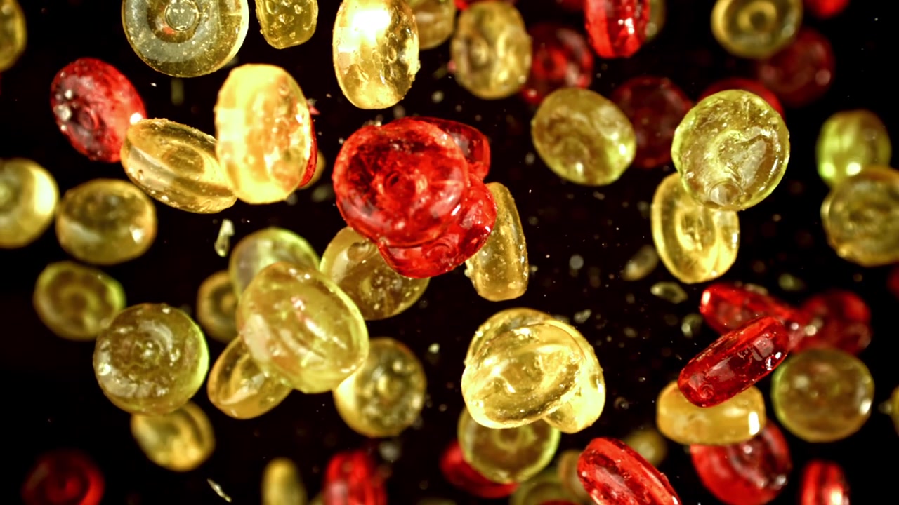 Caramelos rojos y amarillos cayendo a cámara lenta