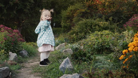 una niña muestra un beso en el aire y camina por un sendero en el parque. caminata de otoño