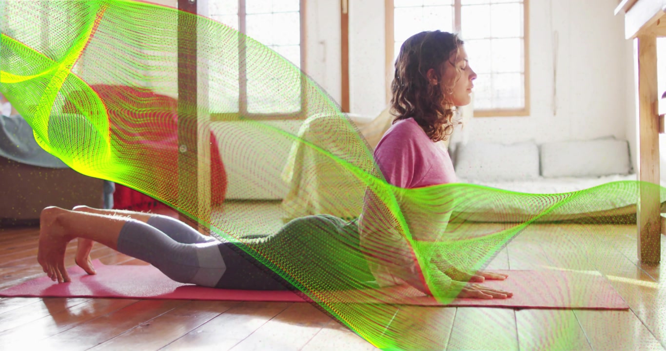 Woman pressing arms on pink mat and arching into cobra pose while ribbons emphasizing spine stretch