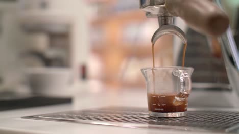 Espresso-machine-drips-and-pours-fresh-brew-into-glass-cup,-detailed-closeup