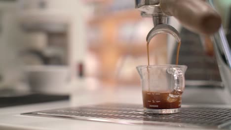 espresso machine drips and pours fresh brew into glass cup, detailed closeup