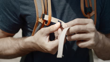 Close-up-shot-of-a-hiker-puting-a-pin-on-his-orange-backpack-strap-and-clips-it-back