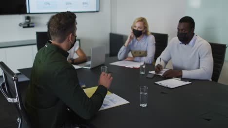 grupo diverso de colegas de negocios con máscaras en discusión en la sala de reuniones