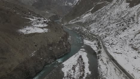 aerial over river in hunza valley with snow hillside landscape