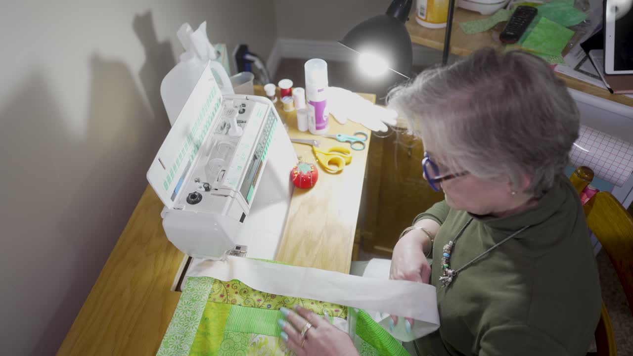 재봉틀에 바인딩과 함께 퀼트 블록을 바느질 수석, 은퇴한 여자