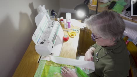 anciana jubilada cosiendo bloques de edredón junto con encuadernación en una máquina de coser