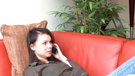Mujer-Pensativa-Hablando-Por-Teléfono-Sentada-En-El-Sofá
