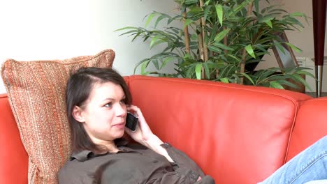 pensive woman talking on phone sitting on sofa