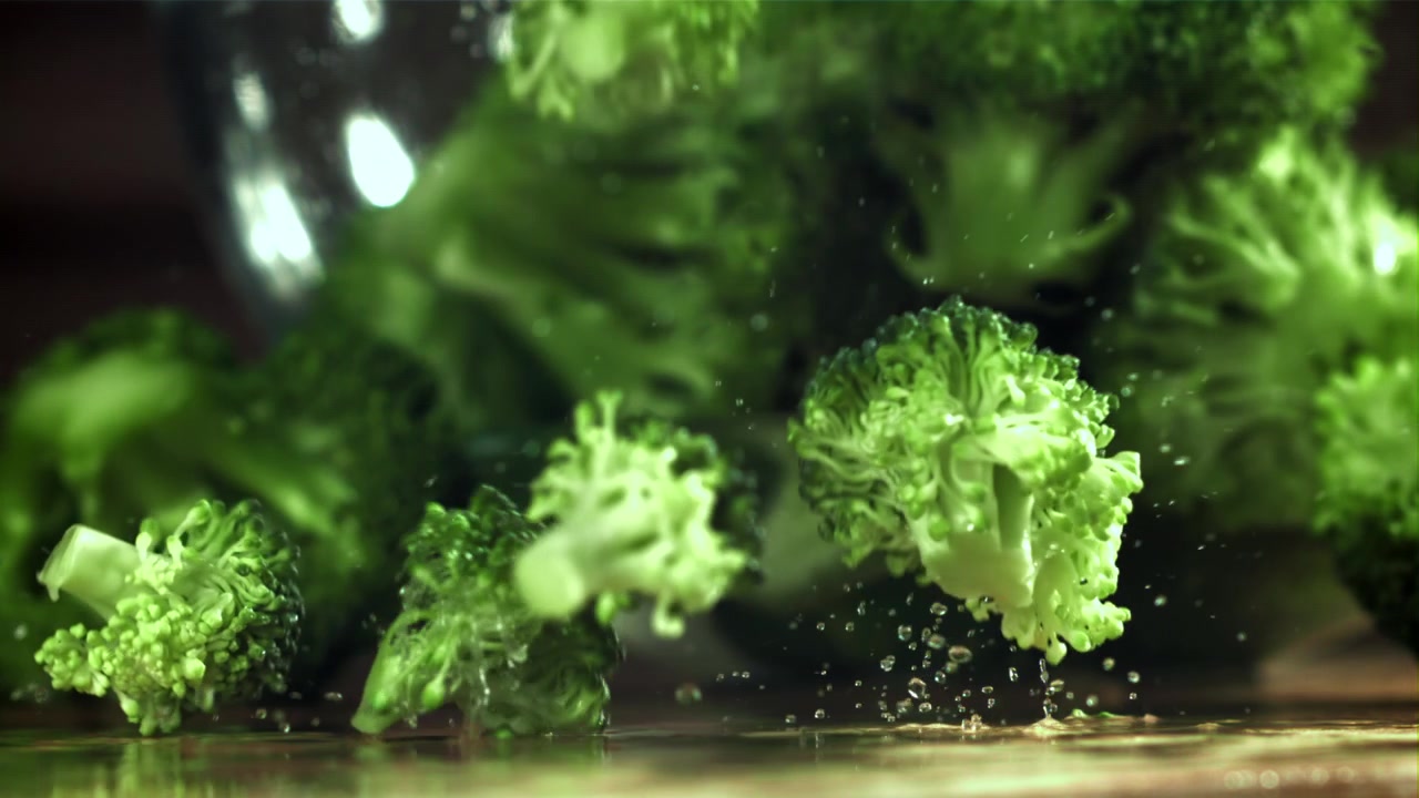 Rallentatore di cimette di broccoli fresche che cadono e schizzano acqua