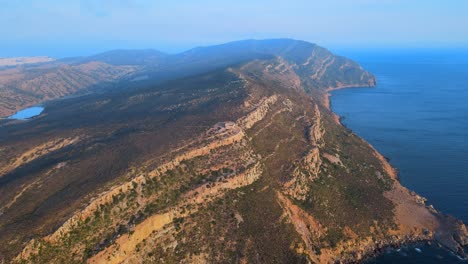 A breathtaking aerial view of Tunisia's rugged Haweria Peninsula, showcasing its dramatic cliffs, lush greenery, and the deep blue Mediterranean Sea.